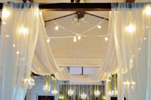 A room with white drapes and chandeliers.