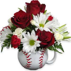 A bouquet of red roses and daisies in a baseball mug.