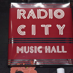 A sign for radio city music hall on a brick wall.