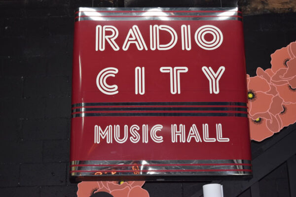 A sign for radio city music hall on a brick wall.