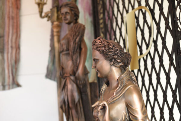 Bronze statues of a woman and a man on a wall.