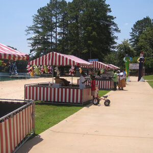 A group of people sitting on a Carnival Booths next to a pool.