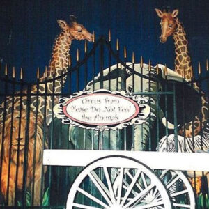 A giraffe and a zebra in front of Circus Animal Flats gate.