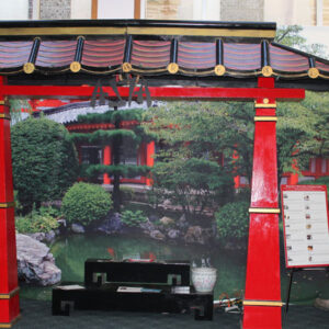 A red and gold Large Tori Gate with a bench in front of it.