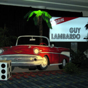 A red and white Vintage Car Flats in front of a palm tree.