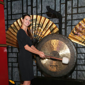 A woman holding a bat in front of a Gong.