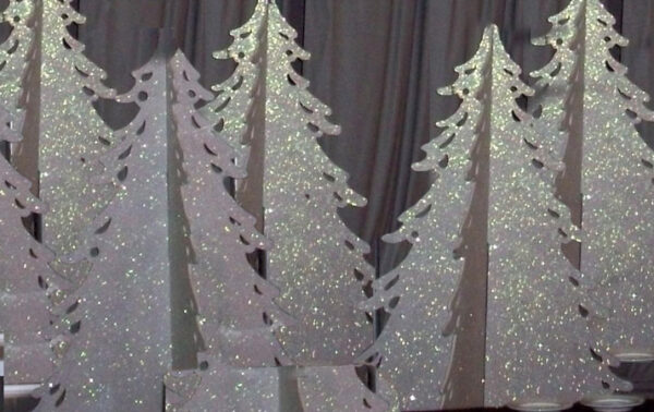 A group of White Slotted Christmas Trees with glitter on them.