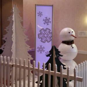 A Winter Scene is standing next to a white picket fence.