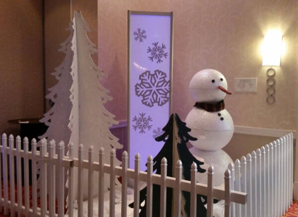 A Winter Scene is standing next to a white picket fence.