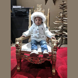 A young boy sitting on a Baby Throne.