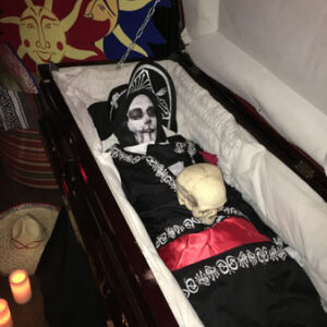 A mexican skeleton in a Caskets with candles.