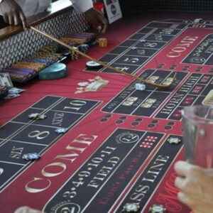 A group of people playing craps tables at a casino.