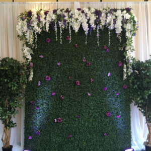 A Flowery Faux Boxwood Wall decorated with flowers and greenery.