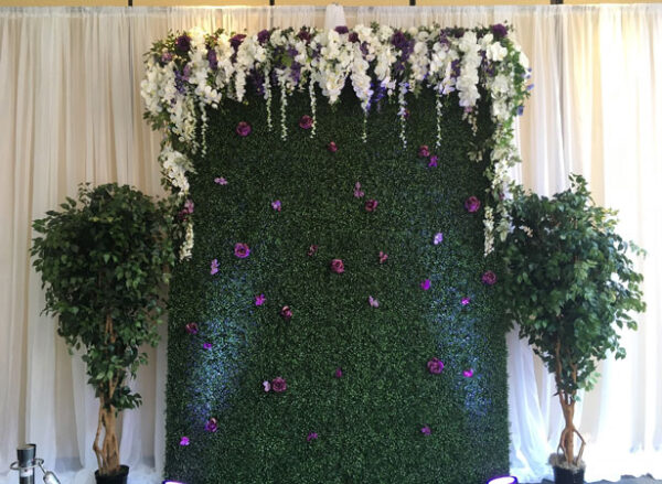 A Flowery Faux Boxwood Wall decorated with flowers and greenery.