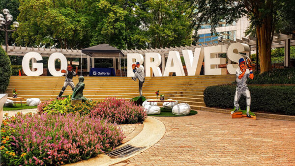 A statue of a baseball player in front of Block Letters that says go braves.