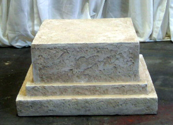 A Decorative Pedestal sitting on a table in front of a curtain.