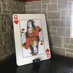 A giant queen of spades playing card is displayed on a table.