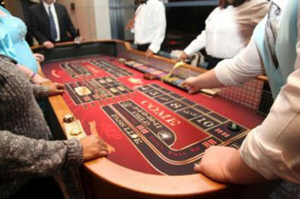 A group of people playing craps tables at a casino.