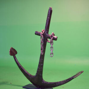 An Original Ship's Anchor with chains on a green background.