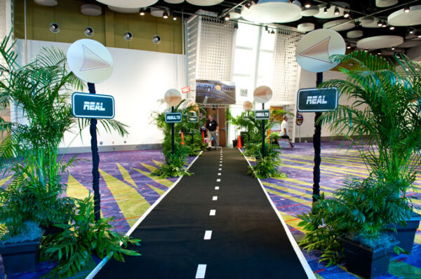 A walkway with palm trees and plants in front of it.