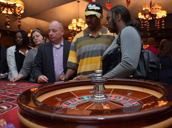 A group of people standing around a roulette table.