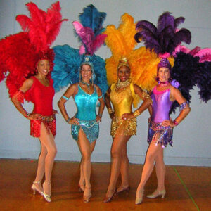 Four Live Showgirls in colorful feathered costumes posing for a photo.