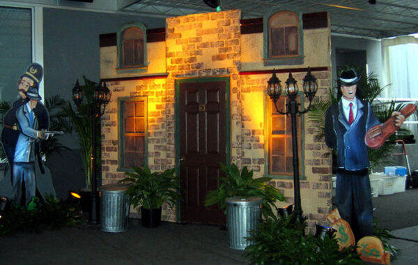 A man dressed in a tuxedo is standing in front of a house.