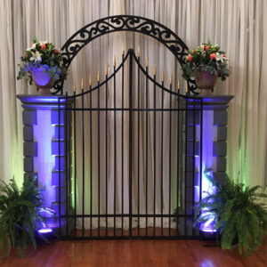 An iron gate with plants and flowers on it.