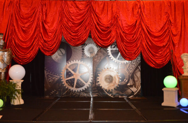 A stage set with a red curtain and a clock.