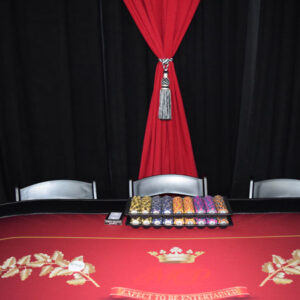 A Texas Hold'em table with a red curtain and chairs.