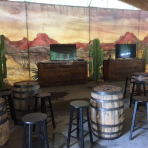 A bar with stools and a Western Canvas Backdrop on the wall.