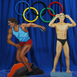 A statue of a man in a bikini standing next to the Olympic Games. Olympics theme decor