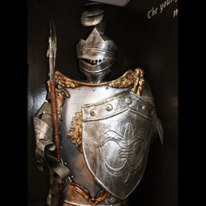 A knight is holding a Fire Eater and shield in front of a wall.