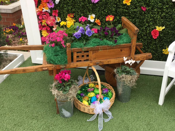 A Small Flower Cart filled with flowers and easter eggs.