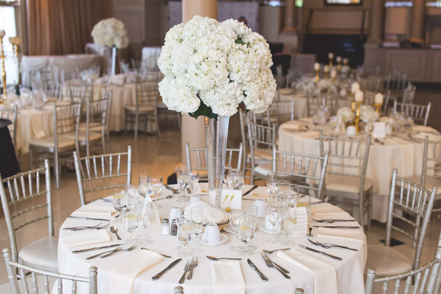 A white and gold wedding reception with white flowers featuring event table rentals.