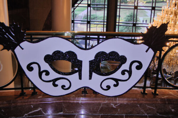 A black and white Mardi Gras mask on a railing.