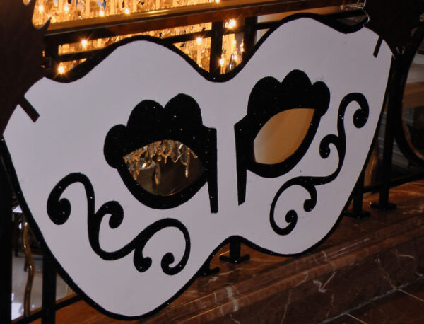 A black and white Mardi Gras mask on a railing.