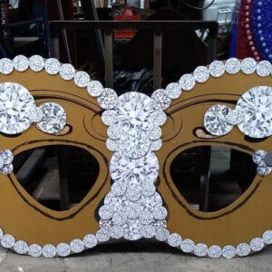 A gold and white Mardi Gras mask with diamonds on it.