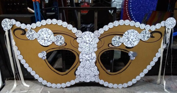 A gold and white Mardi Gras mask with diamonds on it.