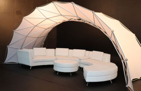 A Portable Event Space Arch provides a portable event space with a white couch and chairs.