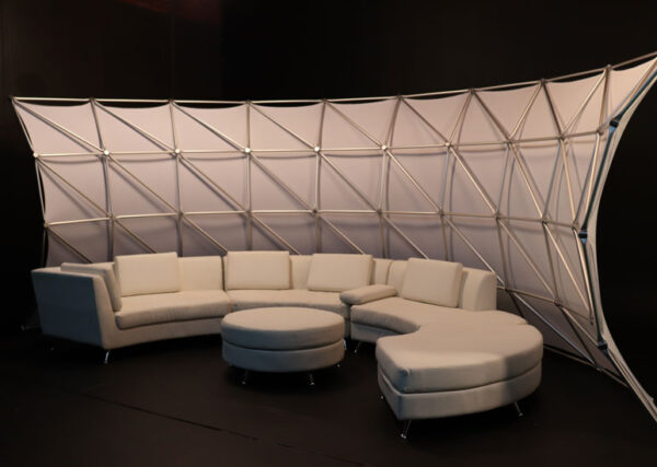 A white couch and table in a room with a Portable Event Space Arch.