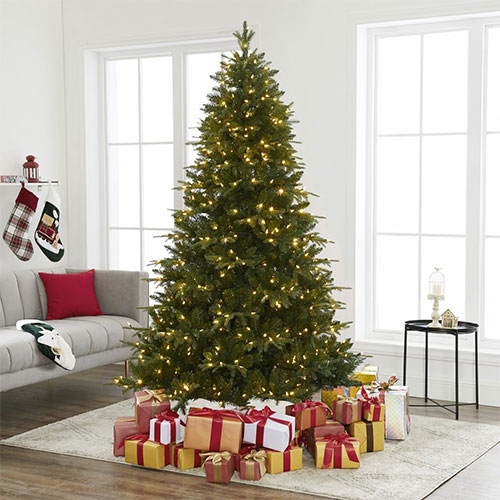 A Christmas Trees with presents on it in a living room.