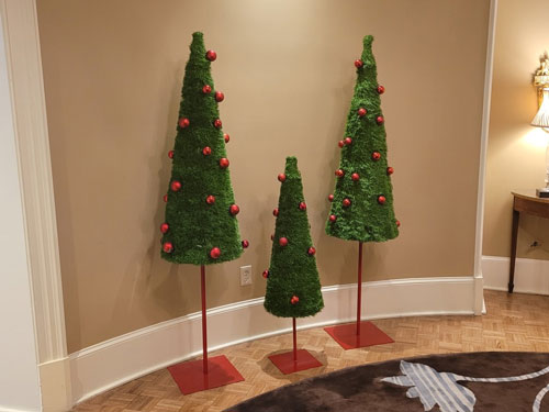 Three Christmas Trees on stands in a room.