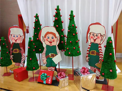 A group of elves standing in front of a christmas tree.