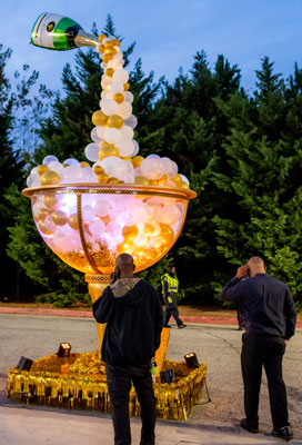 A group of people standing near a float with balloons on it. Atlantic station light the tree