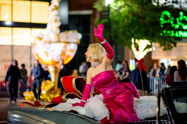 A woman in a pink dress waving in a car. Atlantic station light the tree