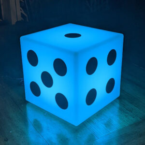 A blue Glow Dice sitting on a wooden floor.