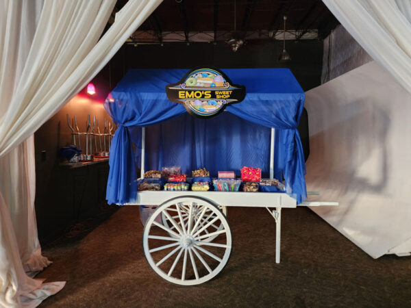 A white Candy Cart with a blue curtain in front of it.