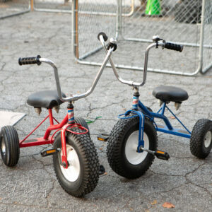 A blue tricycles and a red tricycles.