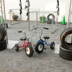 A pair of tricycles are parked next to a set of tires.